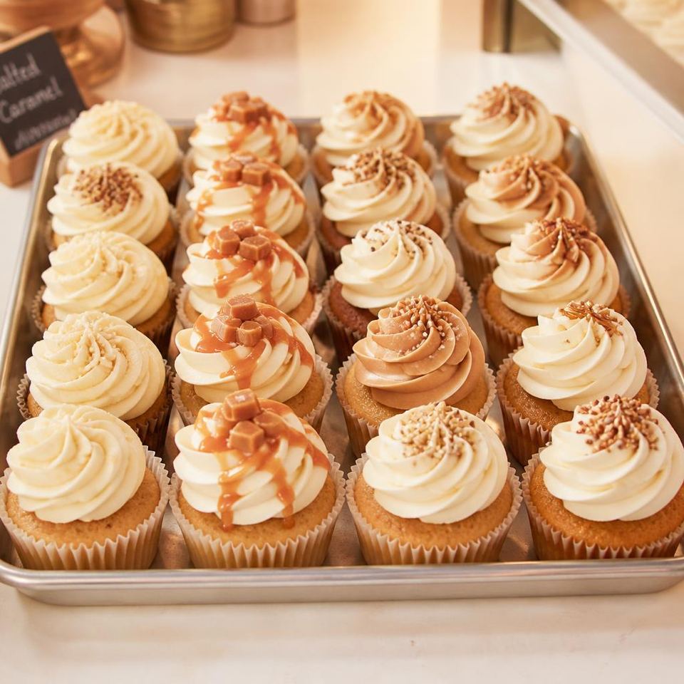 Bakery tray of freshly frosted cupcakes with ivory and caramel buttercream swirls, Gurgaon